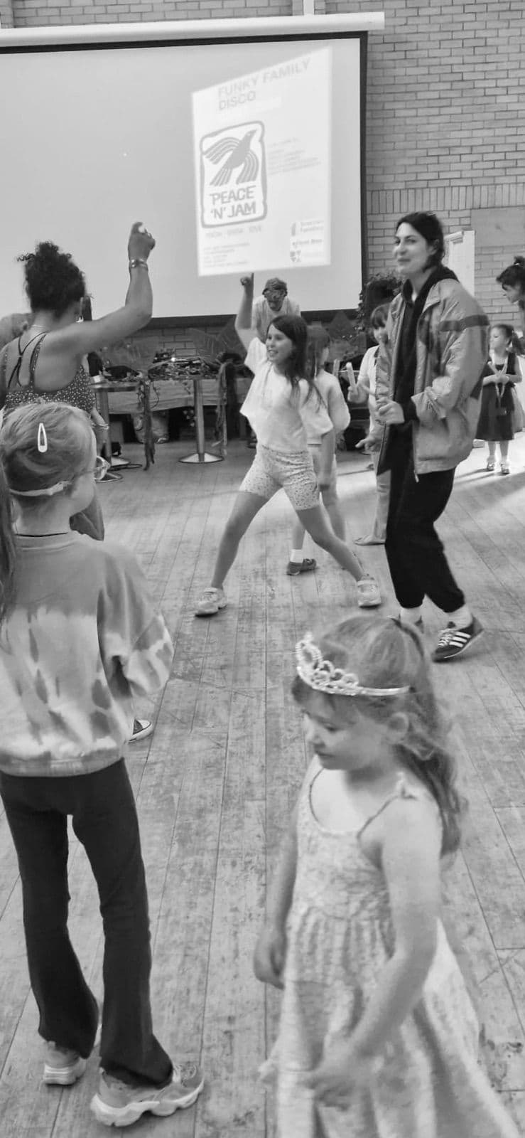 Dancers lit by a projection on the wall, in black and white.