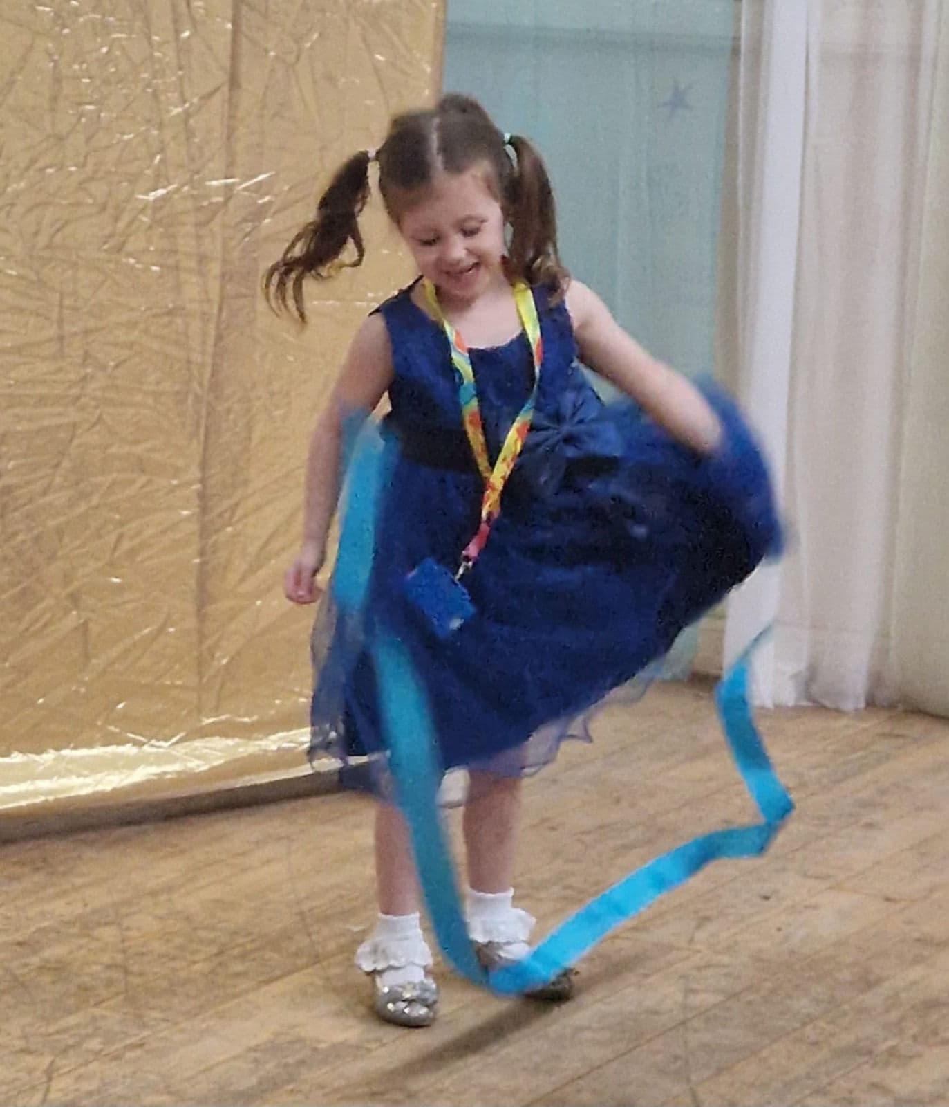 A child twirling a coloured ribbon on the dance floor.