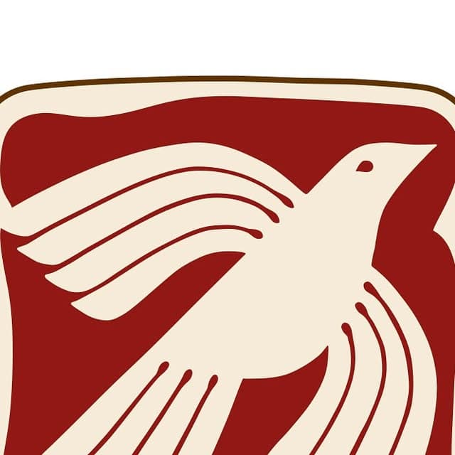 A cream dove in flight with outstretched wings on a deep red ground, drawn in a bold woodcut style