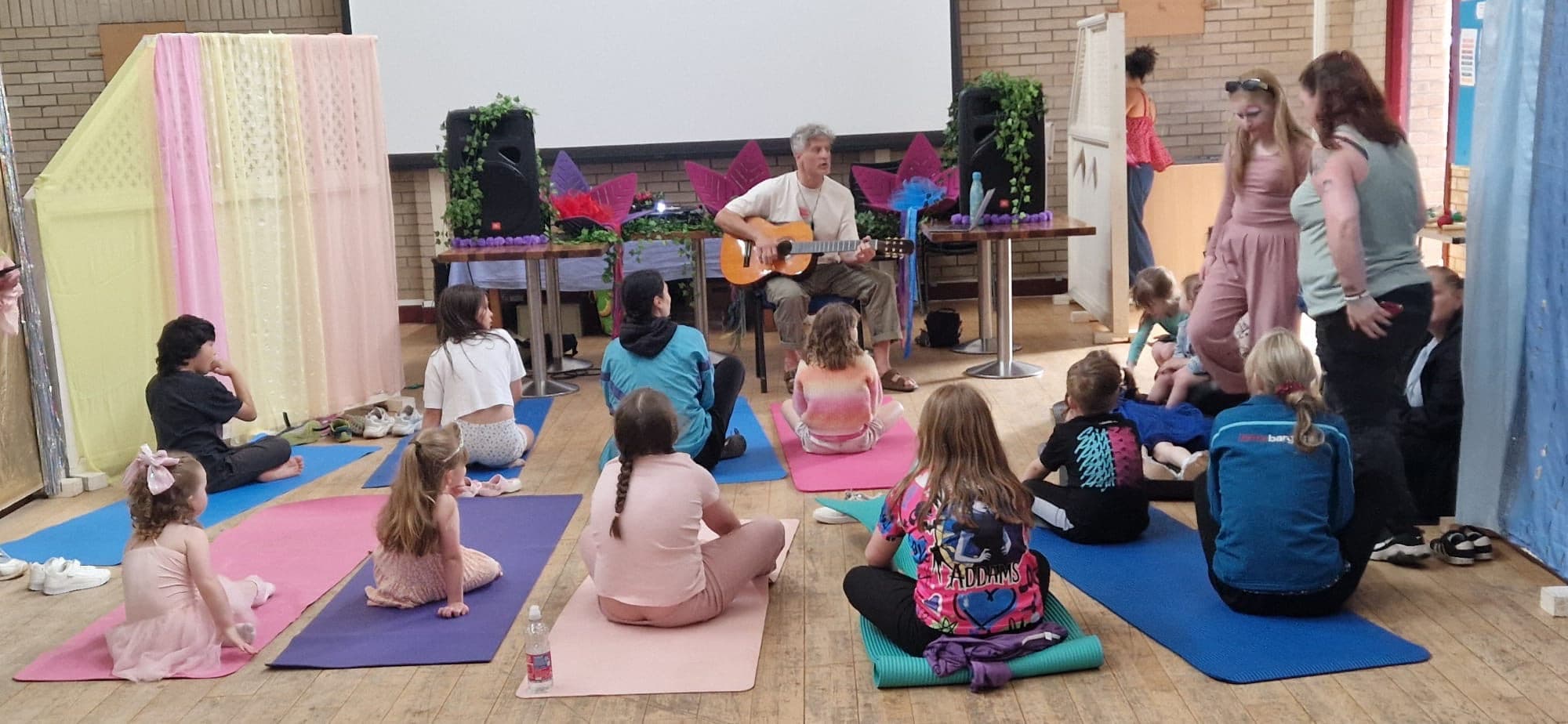Families sitting on yoga mats for a gentle song together.